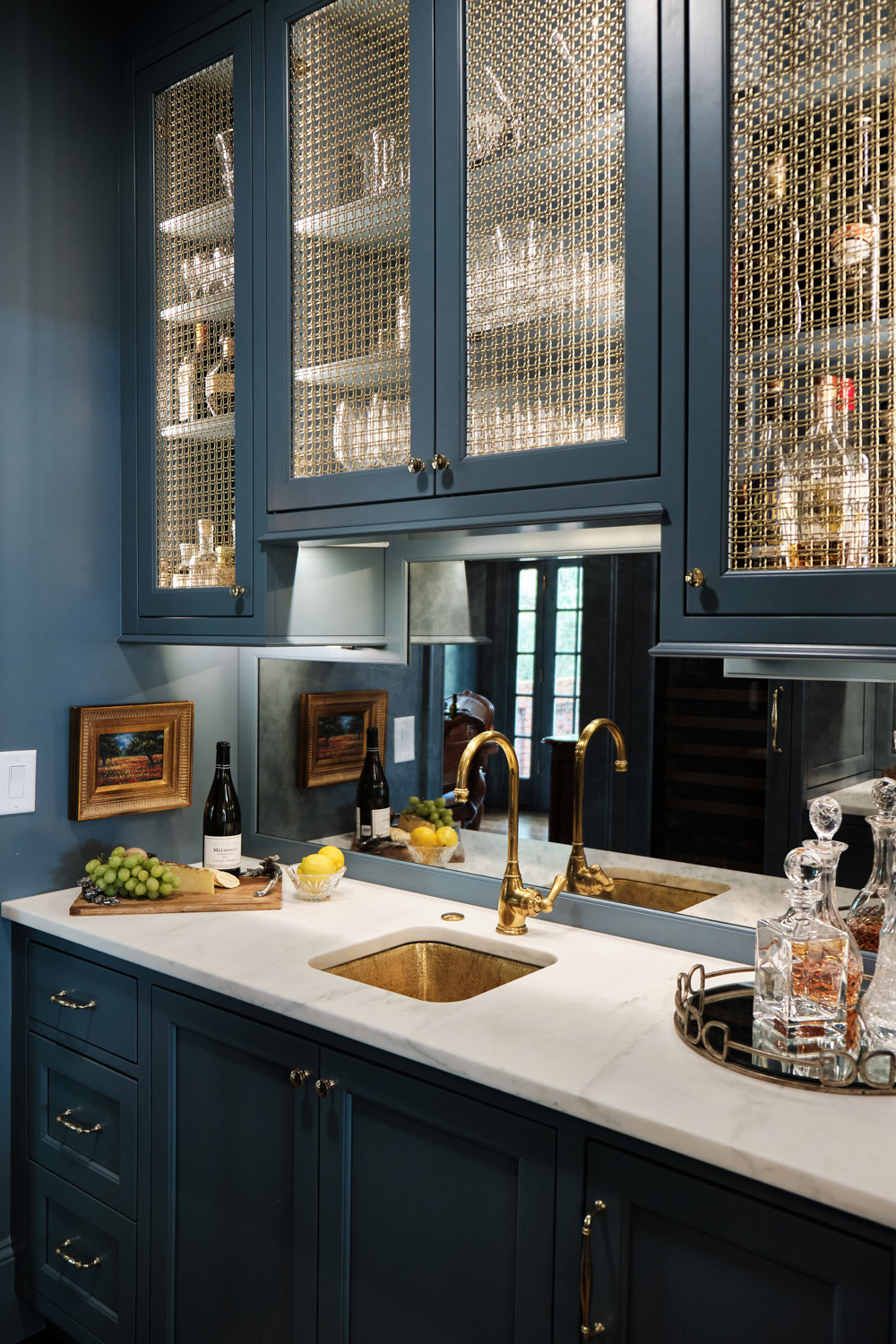built in dark blue cabinets with a marble top and hammered brass sink in the custom bar area 