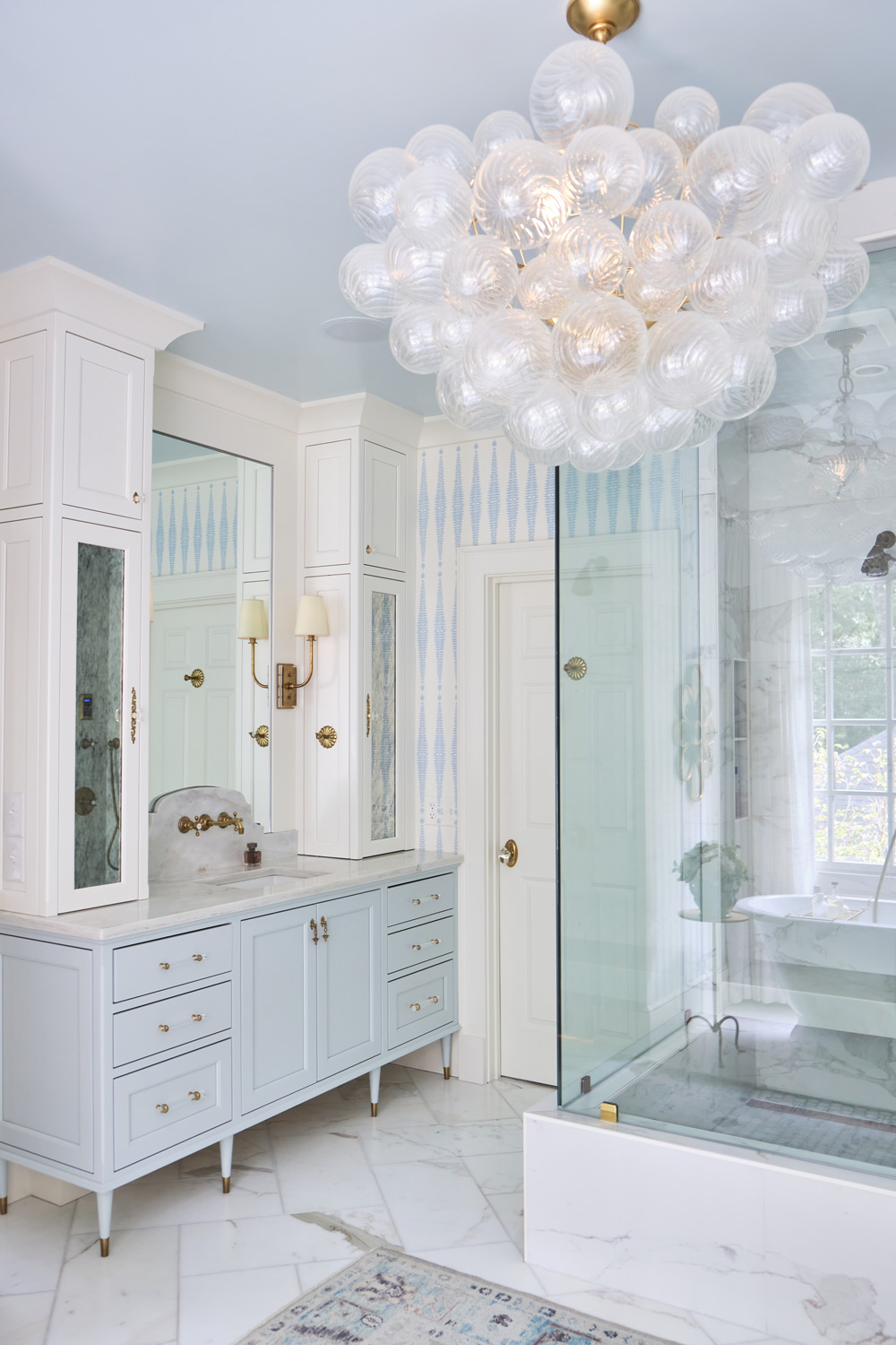 a mirrored built in vanity is displayed with the shower at the center of the bathroom and the mid century modern chandelier above