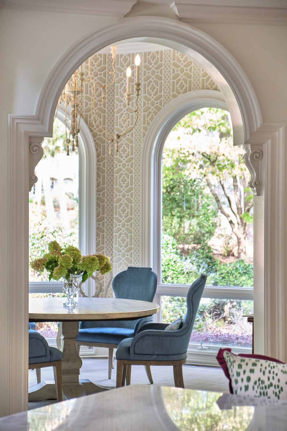 a view of the breakfast area with patterned wallpaper and blue chairs connecting it to the kitchen
