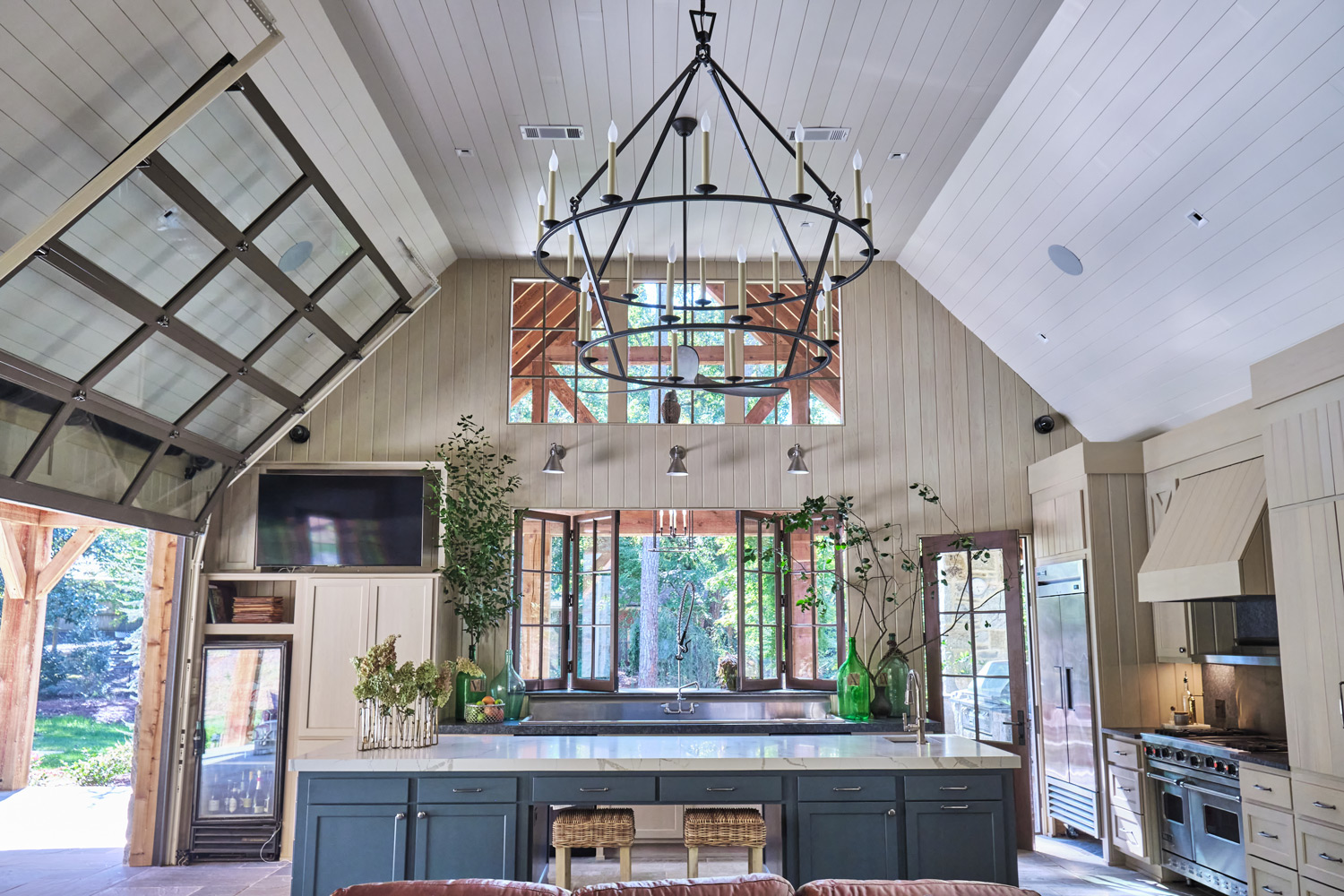 a wide view of the interior of the pool house looking into the kitchen with garage doors up