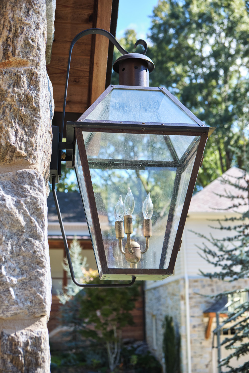 an iron lantern hangs from a stone column at the pool house entrance